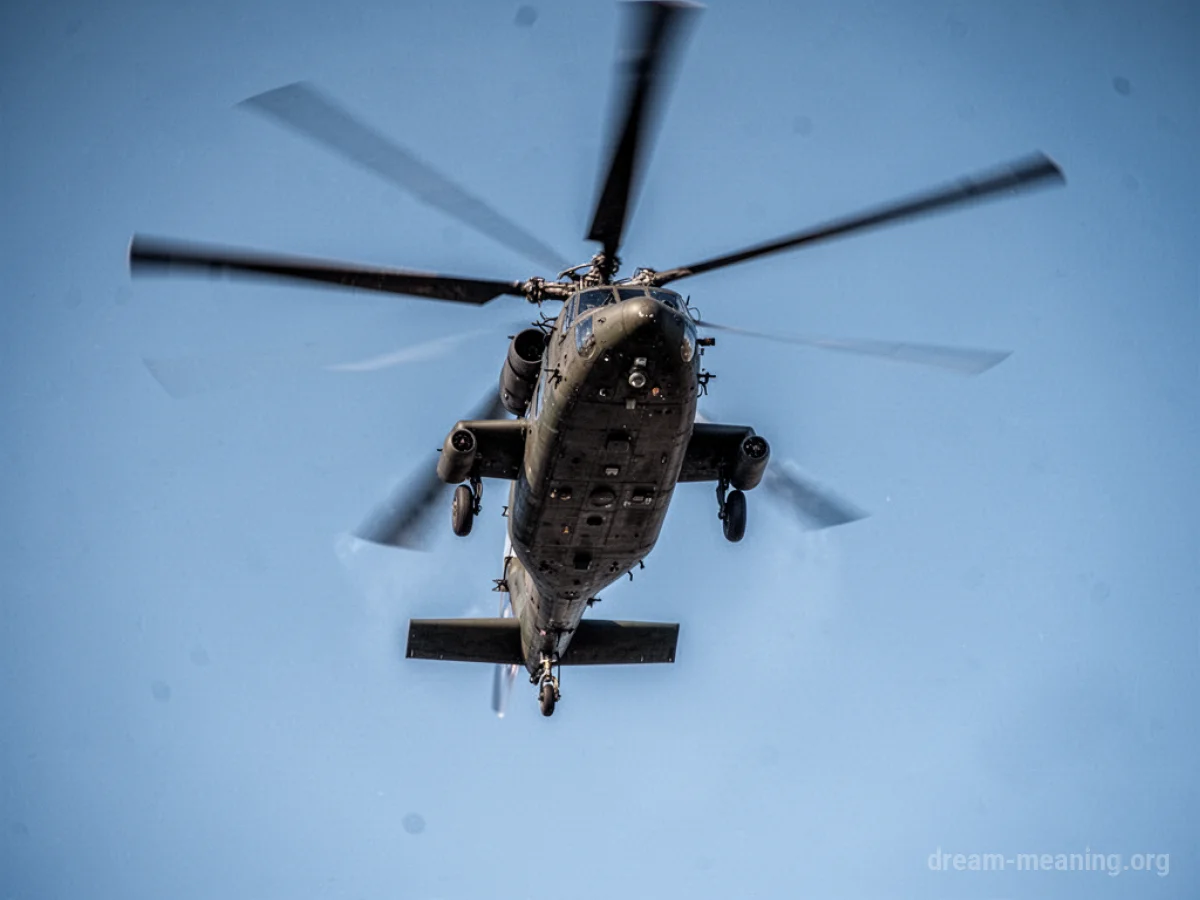 A military helicopter flies in a clear blue sky.