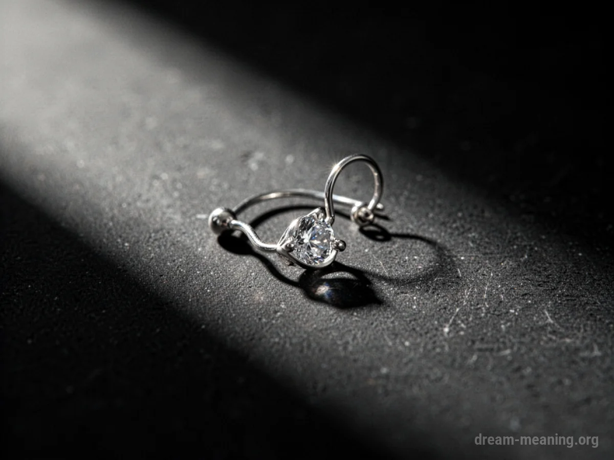 A silver earring on a dark, textured surface.